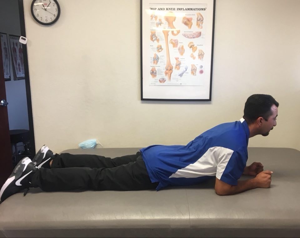 A physical therapist demonstrates the cobra stretch, otherwise known as the prone press up