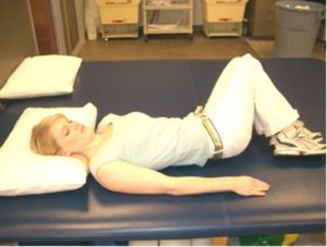 A lady demonstrates the supine trunk rotation for middle back pain.