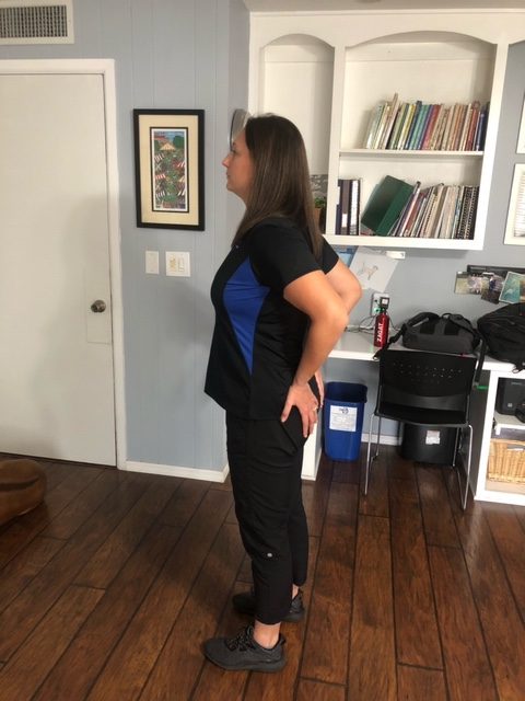 A woman demonstrating the hands on hips stretch