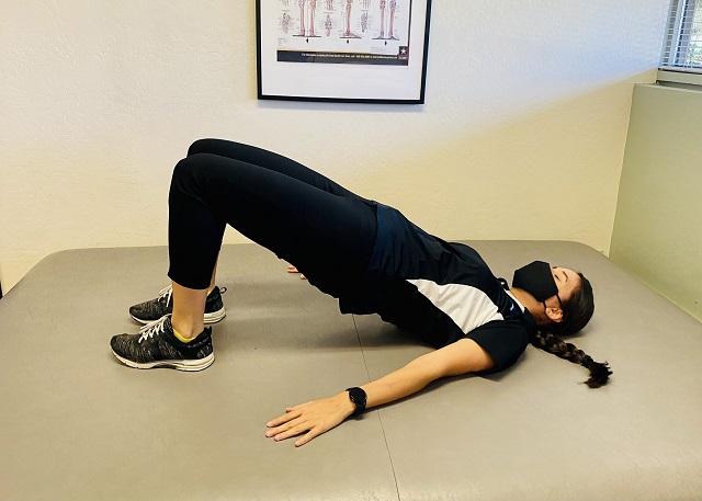 A PT technician performing the glute bridge exercise.
