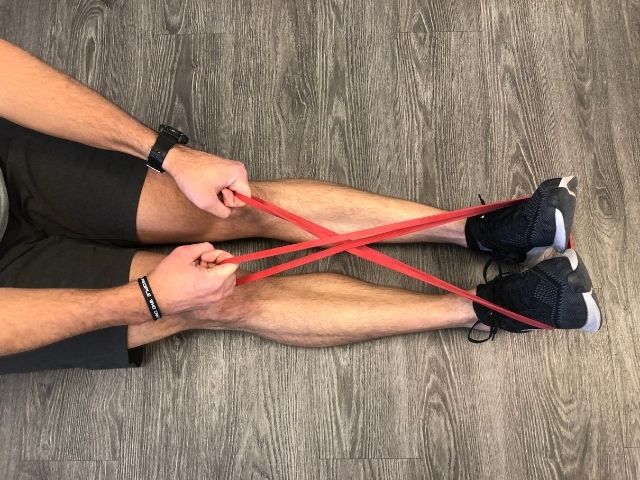 Exercise band crossed in front of the feet for the face pull.