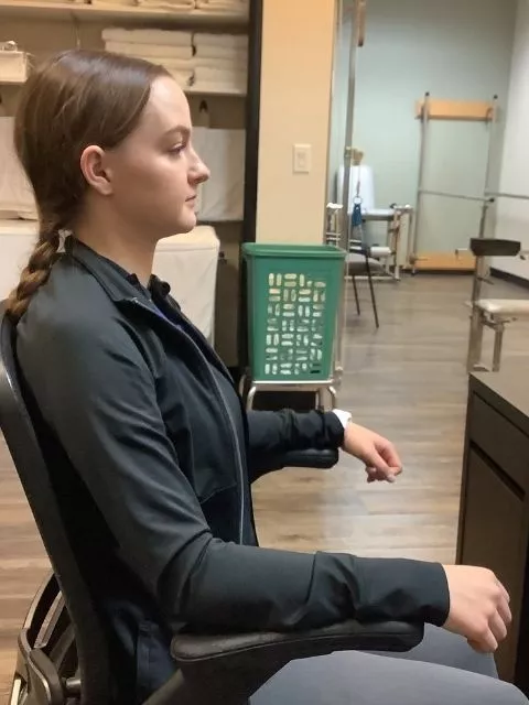 A woman with proper posture sitting at a computer.