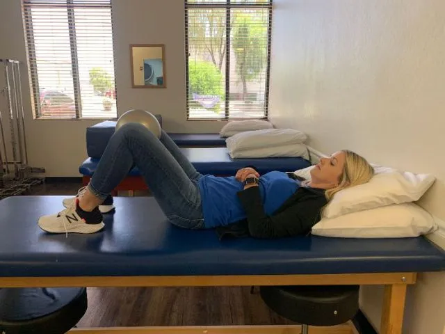 A ball placed between a patient's legs for the hip abduction exercise.