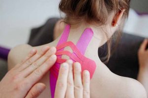 A woman receiving Kinesio tape treatment for her neck pain.