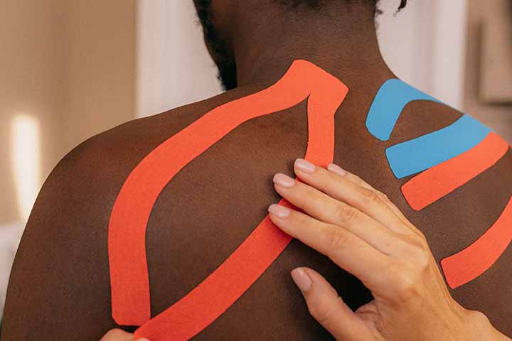 A man receiving Kinesio tape treatment for his scapula pain.