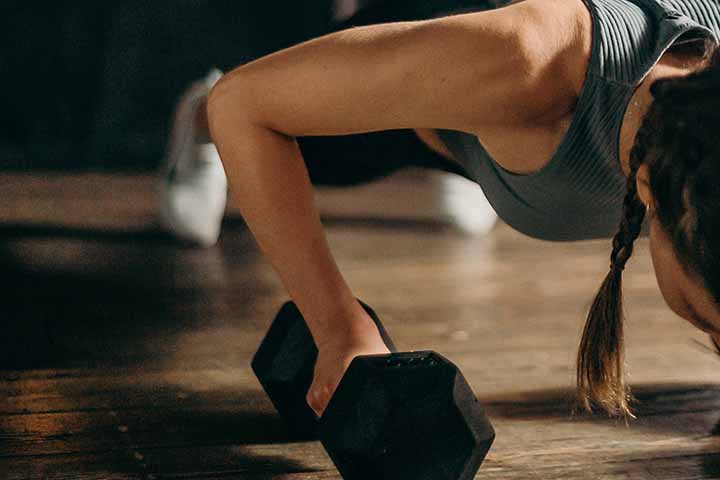 A woman doing push ups on a set of dumbbells.