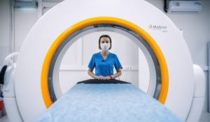 An MRI technician standing next to an MRI machine at an imaging center.