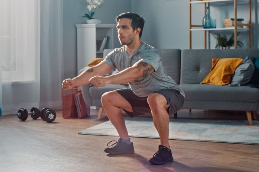 A man doing squats during a micro-workout in his living room.