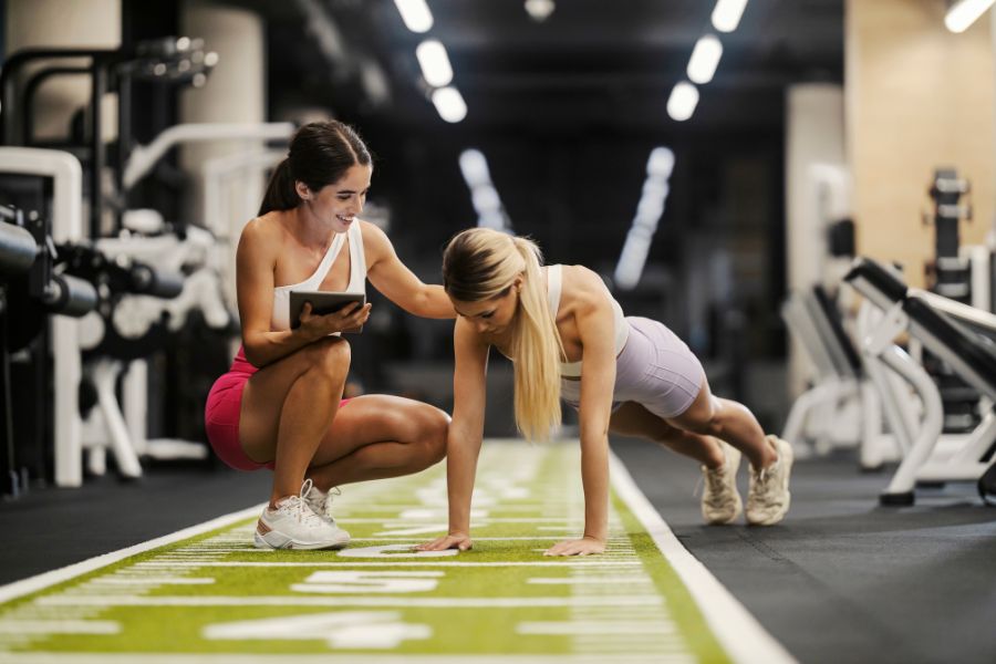 A woman working with a personal trainer in a gym.