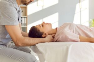 A patient undergoing manual therapy on her neck with a physical therapist.