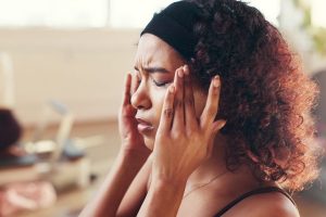 A woman experiencing a tension headache at work.