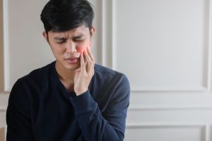A young man suffering from TMJ pain.
