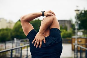 A man stretching his shoulder during his exercise routine.
